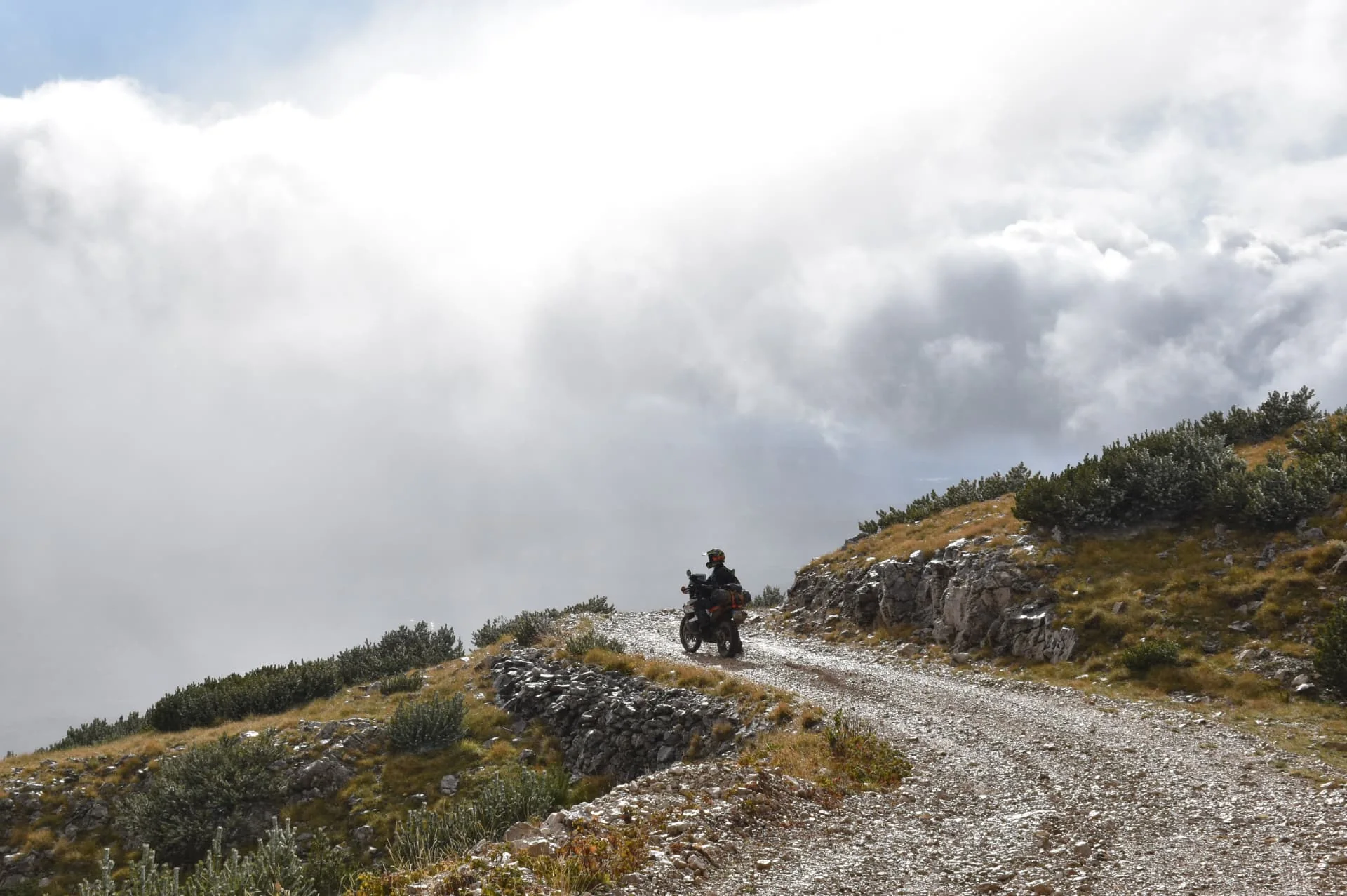 Motorcyklist på en slingrande grusväg i bergen